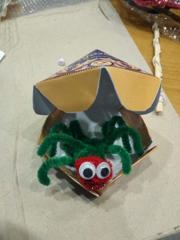 Pipe cleaner spider sitting in an open chocolate frog box